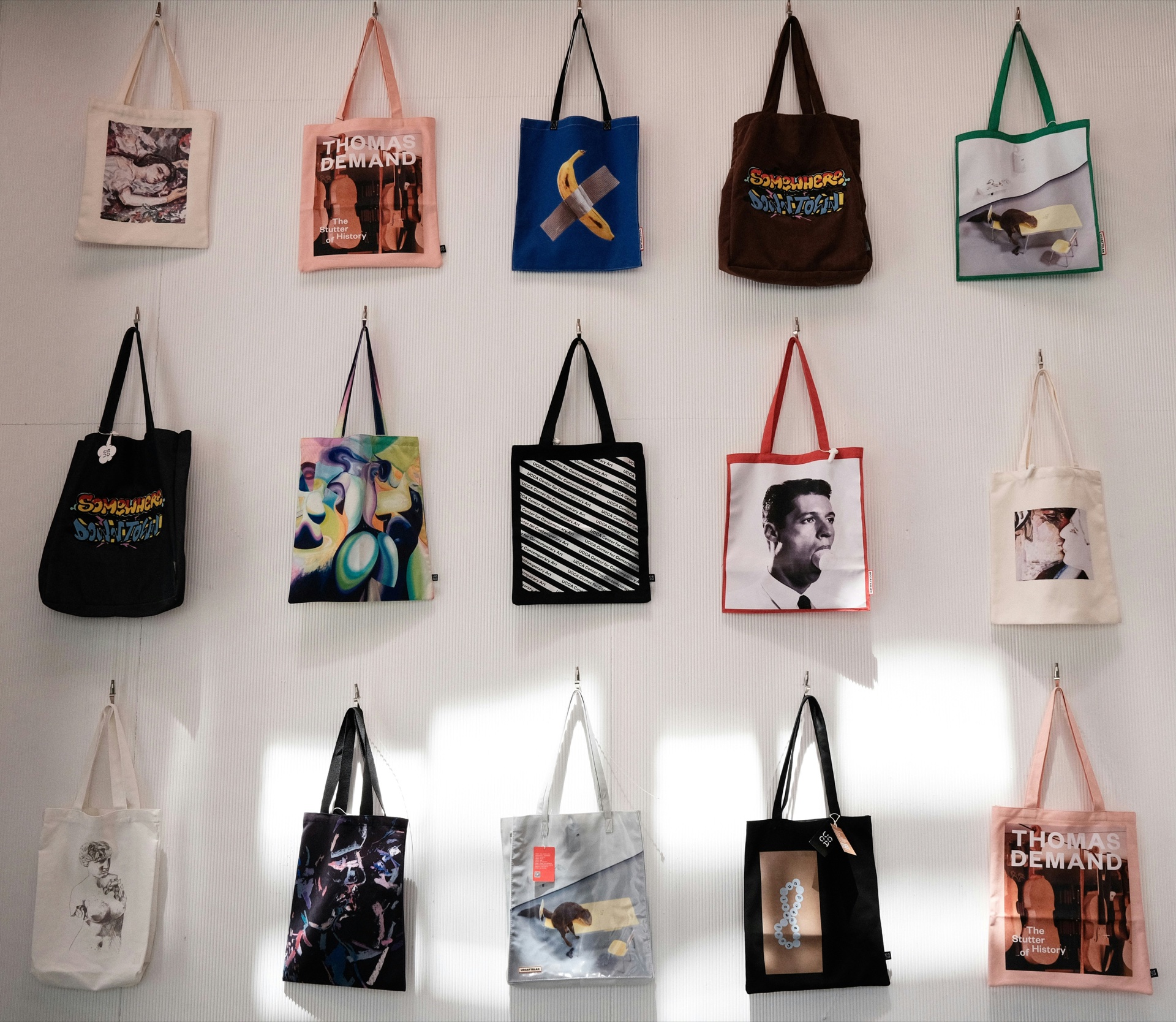 Stack of natural cotton tote bags with bold artwork screen-printed on the front