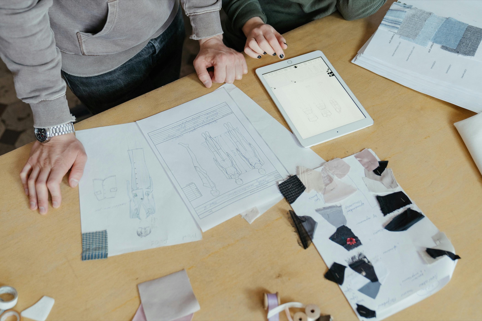 Open sketchbook with fashion illustrations and fabric swatches representing the early stages of starting a clothing line