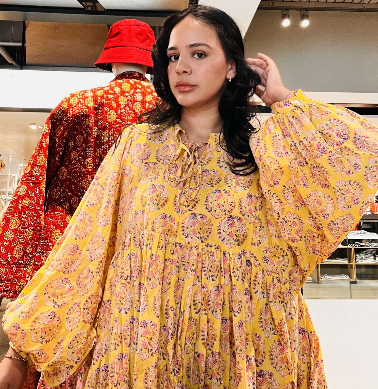 A customer wearing a yellow block-print tiered DesignerFriday dress on the shop floor.